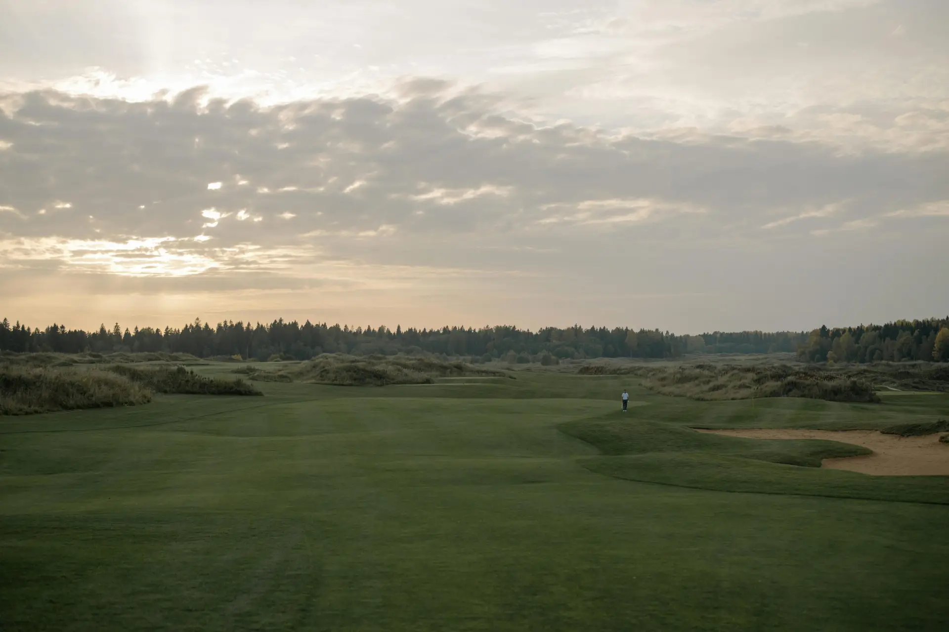 Expansive twilight view of a tranquil golf course with lush greenery under a dramatic sky.