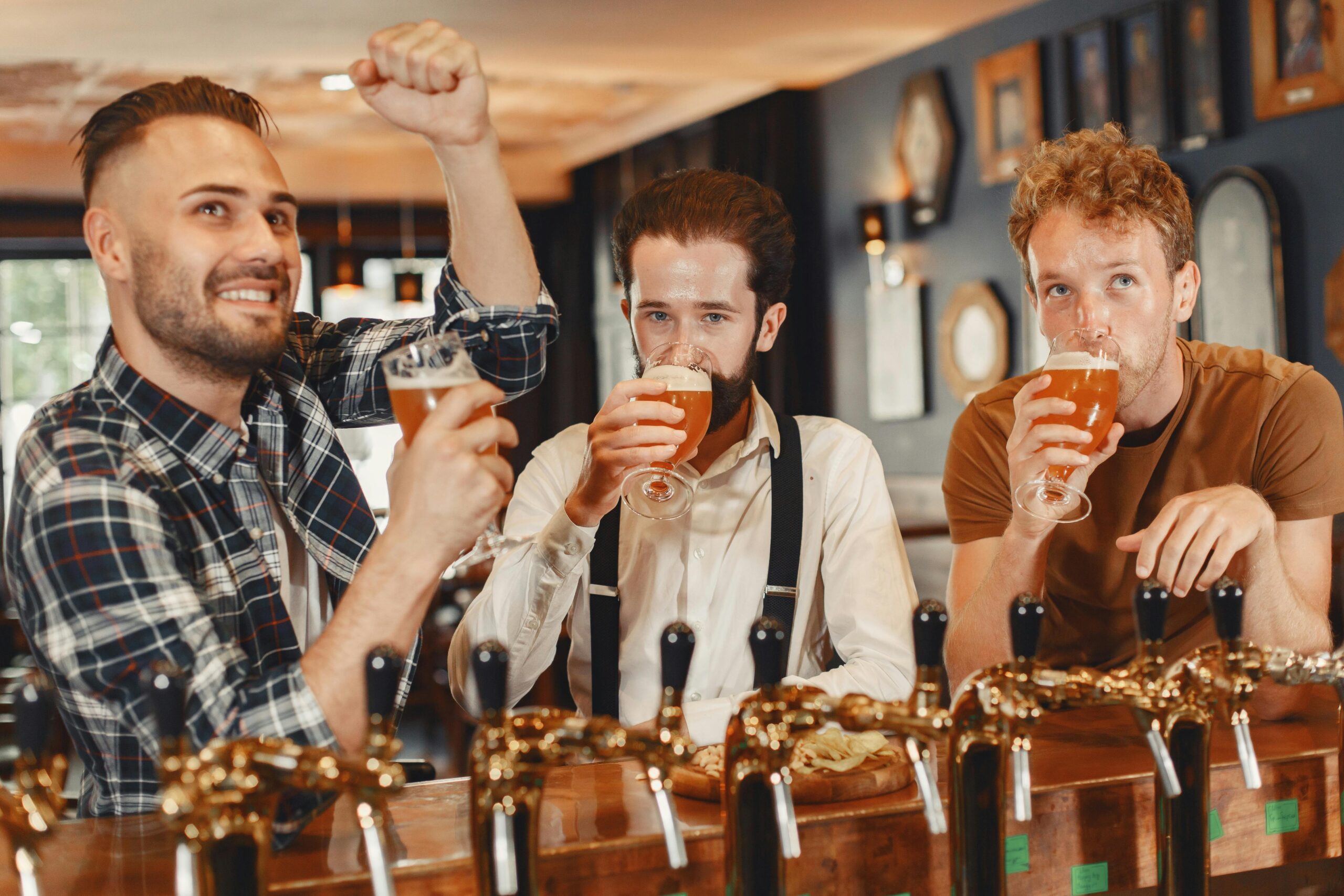Three men enjoying craft beer together at a cozy indoor bar setting.